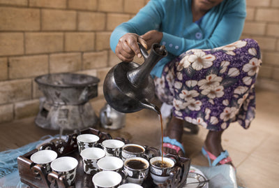 Woman Pouring Coffee into Cups on a Tray